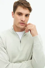 Buzo de punto color gris claro con medio cierre, cuello alto y logo bordado.