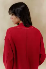 Chaqueta de punto color crudo con solapa ancha acanalada terminada con cadenetas en contraste negro. Tiene calce relajado, hombros caídos, largo a la cadera y manga larga.