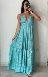 Vestido largo turquesa con estampado cachemir, escote halter y espalda descubierta. Tiene corte imperio con falda amplia de dos niveles.