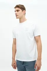 Remera blanca de manga corta con cuello redondo y estampado pequeño en el pecho con una columna griega y texto en color celeste.