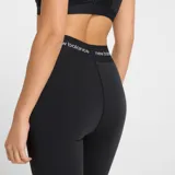 Calza de entrenamiento negra con cintura alta y logo de New Balance, confeccionada con tejido elástico de alto rendimiento.