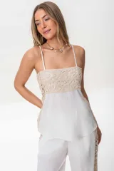 Musculosa blanca de lino italiano con breteles finos regulables y detalle de broderie en el lateral. Se ajusta en la espalda con cintas.