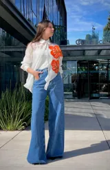 Camisa blanca traslúcida con botones y estampado de flores anaranjadas.