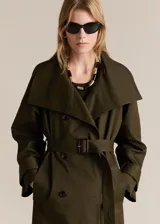Trench coat verde militar con cuello solapa ancho, doble botonadura, cinturón desmontable, trabillas en cintura y puños, dos bolsillos laterales y forro interior.