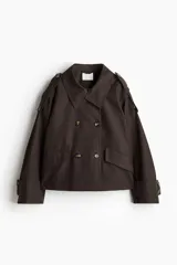 Gabardina corta color marrón chocolate, de corte holgado, con cuello clásico, doble botonadura, charreteras, trabillas abotonadas en los puños, bolsillos delanteros con solapa y pliegue invertido en la espalda. Forrada.