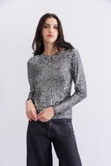 Remera de mangas largas plateada con lentejuelas aplicadas en toda la prenda, escote redondo y forrería interna.