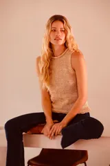 Top dorado tejido en lurex metálico, sin mangas y con cuello redondo.