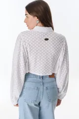 Camisa marrón con estampado de flores blancas, de corte cropped con nudo frontal y mangas largas abullonadas.