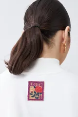 Remera de media polera color crudo, de manga corta y corte recto.