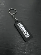 Llavero con dije de metal negro con forma de casco alado, con detalles en blanco. Incluye aro y cadena metálica plateada.