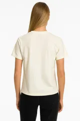Remera de algodón color crudo con estampado de un labial rojo y texto en color bordó que dice "It's OK to wear lipstick". Corte clásico, cuello redondo y mangas cortas.