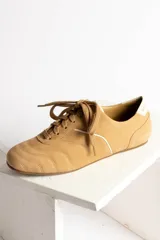 Zapatillas bajas color beige con cordones y detalles en blanco.