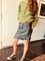 Minifalda negra de cuero con corte irregular y detalles de costuras.
