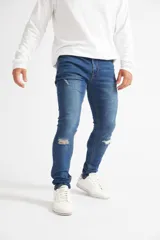 Jean skinny de hombre color negro, ajustado desde la cadera hasta los tobillos, con roturas en las rodillas y logo bordado en el bolsillo trasero.