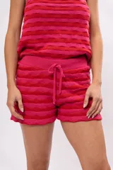 Short tejido a crochet con cintura elastizada y cordón ajustable. Diseño a rayas horizontales en tonos fucsia y rojo.