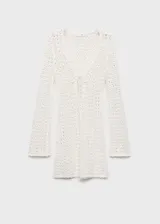 Vestido corto de crochet color blanco, con cuello en pico, mangas largas y cierre de lazo en la parte delantera.