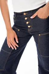 Pantalón de jean azul oscuro, de corte ancho, con bolsillos frontales y traseros. Presenta cierre frontal con botones dorados.