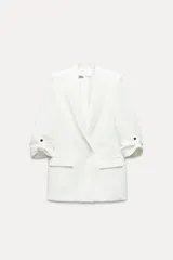 Blazer blanco con cuello solapa y hombreras. Manga por debajo del codo acabada en vuelta con trabilla y botón dorado. Bolsillos delanteros con solapa.
