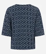Blusa tipo bata de mangas cortas, confeccionada en viscosa con estampado de follaje en blanco sobre fondo azul marino. Tiene escote en V con detalle de abalorio en el centro.