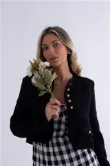 Chaqueta corta negra con botones dorados y bolsillos frontales.