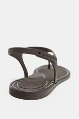 Sandalia plana color marrón con efecto engomado, tira delantera para el dedo y cierre con tira ajustable al tobillo.