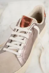 Zapatilla combinada de cuero en colores peltre y beige, con detalles metálicos y cordones.