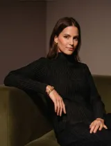 Blusa negra de manga larga con cuello alto y textura plisada.