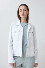 Campera de jean blanca con cuello clásico, bolsillos con solapa abotonados en el pecho y cierre frontal con botones metálicos. Corte recto.