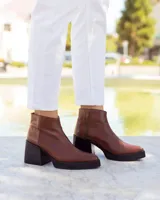 Botines de cuero marrón, hechos a mano en Uruguay, con plataforma delantera y taco ancho y alto de color negro. Presentan un detalle de textura de piel de reptil en la parte superior del talón y cierre lateral con cremallera.