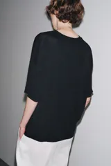 Remera blanca de punto liso, corte amplio, cuello redondo y manga corta.