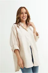 Camisa color crudo, de corte holgado y mangas largas con botón para sujetar.