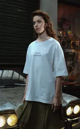 Remera blanca de corte oversize con cuello redondo y manga corta. Presenta un estampado minimalista en el pecho con la frase "Au revoir, shoshanna!" en tipografía negra.