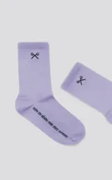 Medias de caña media color lila con detalle de tijeras y texto "Ropa sin género para seres humanos".