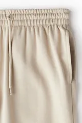 Pantalón de jogging color beige, de corte recto, con cintura elástica ajustable con cordón y puños acanalados.