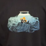 Remera negra de manga corta con estampa de pecera con peces y olas. Confeccionada en algodón orgánico.