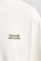 Camiseta relaxed fit de algodón color crudo, con cuello redondo y manga corta. Estampado con la frase "Find trails not excuses" en el pecho.