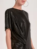 Vestido corto de manga corta, color negro con brillo metálico, confeccionado en lurex. Presenta un detalle de nudo o frunce en la parte delantera inferior.