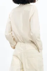 Camisa color crema de algodón y lyocell, con cuello solapa, manga larga con puños y bolsillo de parche en el pecho.