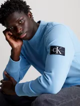 Buzo celeste de algodón, cuello redondo con inserción en V, puños y dobladillo de punto acanalado e insignia del monograma de Calvin Klein en la manga.