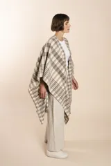 Ruana marrón con diseño a cuadros blancos, terminación envivada y flecos cortos.