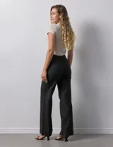 Pantalón de jean blanco de pierna ancha, tiro alto, pretina con pasadores, botón y cierre. Delantera y trasera con bolsillos.