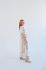Vestido largo color beige con estampado de flores color salmón, corte amplio y mangas 3/4 con botón.