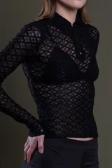Polo de manga larga color negro, confeccionada en encaje con diseño geométrico. Tiene cuello polo con cierre de cremallera y es traslúcida.