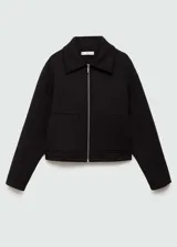 Chaqueta negra corta con capucha gris desmontable y ajustable con cordones. Presenta cuello camisero, cierre de cremallera doble, bolsillos laterales y bajo con goma elástica.