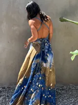 Vestido largo de tela fluida, color verde esmeralda con estampado abstracto en tonos turquesa y detalles dorados. Diseño asimétrico con un solo tirante tejido en el hombro.