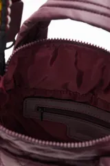 Cartera tipo tote mini acolchada, color negro brillante, con asas cortas y correa larga ajustable. La correa larga es intercambiable y presenta un diseño trenzado multicolor con tonos turquesa, amarillo y negro.