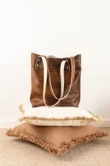 Bolso tote Nómade confeccionado artesanalmente en cuero con pelo color marrón y blanco. Tiene asas de cuero color crudo y forro interior de tela gris.