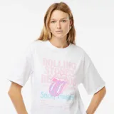 Remera blanca de algodón con estampado frontal de la lengua de The Rolling Stones y texto en color rosa y celeste.