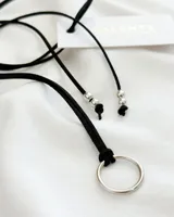 Gargantilla choker de cuero sintético negro con dije circular plateado.