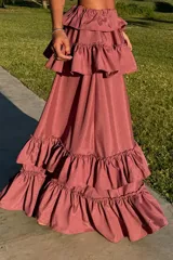 Conjunto de top corto con breteles y falda larga con volados, color rosado. Ambas piezas tienen elástico en la cintura y en el bajo pecho.